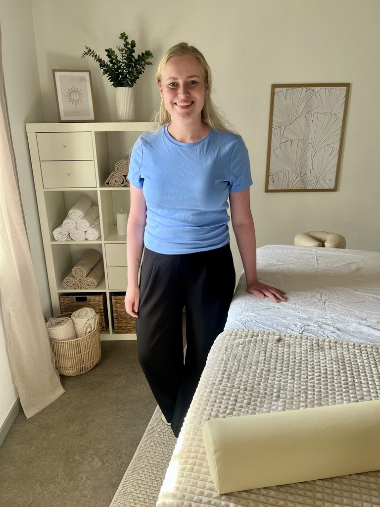 Trine Bork, ejer af Klinik Silkestrøg står ved en massagebriks i sin massageklinik i Løgumkloster, hvor hun udfører blid massage.